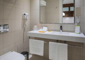 a bathroom with a sink, toilet and mirror at Centro Olaya by Rotana in Riyadh