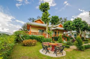 uma casa com uma mesa e cadeiras no quintal em ม่อนชมดอย em Chiang Dao