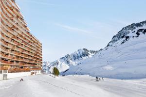 a building on a snow covered slope next to a mountain at Residence Le Montana - maeva Home in La Mongie