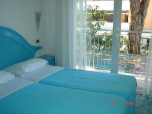 Cama azul en habitación con ventana en Hotel Da Giovanna, en Lignano Sabbiadoro