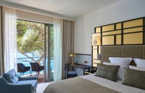 a bedroom with a bed and a chair and a balcony at Hôtel Les Roches Blanches Cassis in Cassis