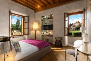 罗马Palm Suites - Small Luxury Hotels of the World的一间卧室，有一张床、一张书桌和两扇窗户