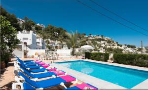 a row of lounge chairs next to a swimming pool at Villa Beniarres Guest House B&B in Moraira in Moraira