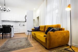 sala de estar con sofá amarillo y cocina en Apartament Tenczyńska, en Cracovia