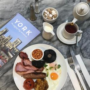 a table with a plate of breakfast food and a book at Galtres Lodge Hotel & Forest Restaurant in York