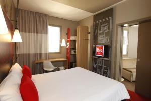 a hotel room with a white bed and a desk at Ibis Sfax in Sfax