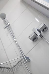a shower head on a white tiled bathroom floor at Hotel Pilar Garni in Cologne