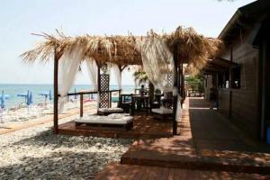 un ristorante con ombrellone e sedie di paglia sulla spiaggia di MarJo a Montegiordano