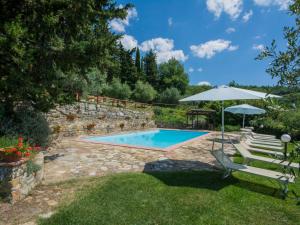 a swimming pool in a garden with chairs and an umbrella at Holiday Home Badia a Passignano-2 by Interhome in Badia A Passignano