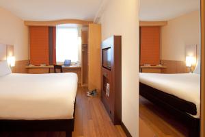 a hotel room with two beds and a television at Ibis London Luton Airport in Luton