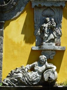posąg kobiety leżącej na ziemi obok żółtej ściany w obiekcie Quinta da Boa Viagem w mieście Viana do Castelo