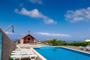 a swimming pool with lounge chairs and a house at A Casa do Lagar in São Jorge
