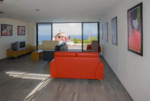 a living room with a red couch and a television at A Casa do Lagar in São Jorge