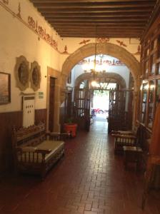 a building with a hallway with benches and an archway at Hotel Los Escudos in Pátzcuaro