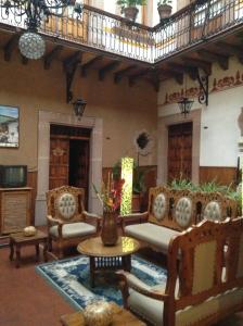 a living room with couches and a table and chairs at Hotel Los Escudos in Pátzcuaro