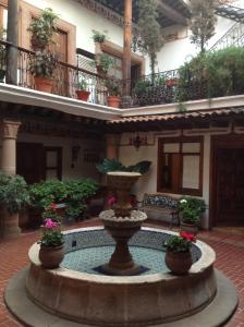 a fountain in the courtyard of a building with plants at Hotel Los Escudos in Pátzcuaro