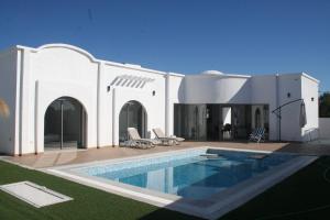 una casa con una piscina di fronte di VILLA NOUR DJERBA plain pied haut de gamme piscine proche de la plage a Midoun