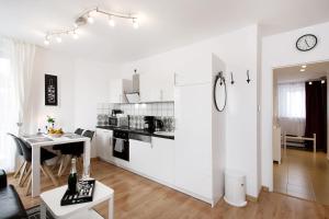 ミエンジズドロイェにあるFamilien Appartement "Ostsee Perle" neu & modernのキッチン(白いキャビネット、テーブル付)、ダイニングルーム