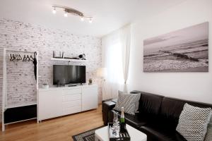 ミエンジズドロイェにあるFamilien Appartement "Ostsee Perle" neu & modernの白レンガの壁のリビングルーム(黒いソファ付)