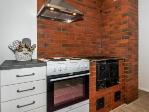 a kitchen with an oven and a brick wall at Holiday Home Hovimäki by Interhome in Vähäsalmi
