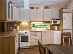 La cuisine est équipée de placards blancs et d'un four avec plaques de cuisson blanches. dans l'établissement Holiday Home Teerenpesä by Interhome, à Tahkovuori