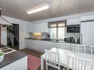 a kitchen with white cabinets and a table and chairs at Holiday Home Hovimäki by Interhome in Vähäsalmi