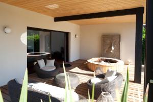 un patio con sillas y una terraza con bañera de hidromasaje. en Villa Margaux, en Fargues-Saint-Hilaire