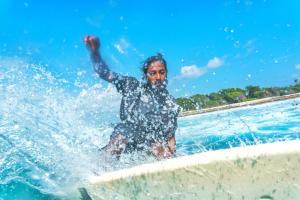 a man is in the water on a surfboard at Aria Holiday Maldives in Himmafushi