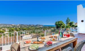 - une table en bois avec de la nourriture sur le balcon dans l'établissement Villa Beniarres Guest House B&B in Moraira, à Moraira