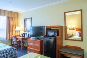 a hotel room with a television and a bed and a desk at Anchorage Inn and Suites in Portsmouth