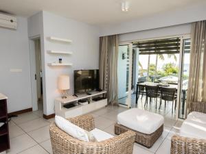 een woonkamer met een televisie en een tafel met stoelen bij AH 5-Seafront,Premium,Luxurious,Serviced Apartment in Triolet