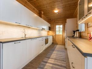une cuisine avec des armoires blanches et un plafond en bois dans l'établissement Holiday Home Telkkä by Interhome, à Vähäsalmi 19 autres photos