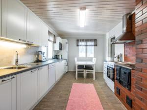 a kitchen with white cabinets and a red rug at Holiday Home Hovimäki by Interhome in Vähäsalmi