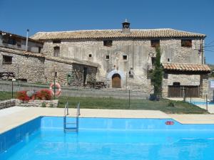 un edificio antiguo con piscina frente a una casa en Casa Paco, en Santa María Lanuez