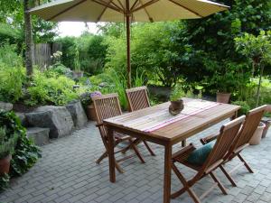 uma mesa de madeira com duas cadeiras e um guarda-sol em Ferienwohnung Geismayr em Dornbirn