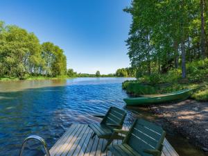dwa krzesła na doku na rzece z łodzią w obiekcie Holiday Home Satakieli by Interhome w mieście Hirsjärvi