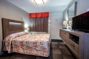 Hotel et Motel Le Chateauguay في مدينة كيبك: غرفة نوم بسرير ومغسلة وتلفزيون