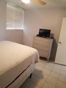 a bedroom with a bed and a dresser with a television at Sea Palm G in Fort Walton Beach