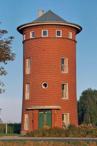 einem großen roten Backsteinturm mit grüner Tür in der Unterkunft Wasserturm Cuxhaven in Cuxhaven