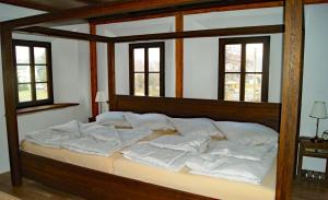 Schlafzimmer mit einem Bett mit weißer Bettwäsche und Fenstern in der Unterkunft Ferienwohnung LATERNENSTUBE mit großem Familienbett für 8 Personen in Leppersdorf
