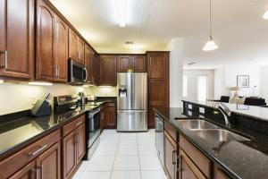 a kitchen with wooden cabinets and a stainless steel refrigerator at Wonderful Vacation Apartment with Balcony at Vista Cay VC5025-103 in Orlando