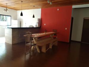 a kitchen with a wooden table and a red wall at Chácara Recanto dos Pássaros in São Thomé das Letras