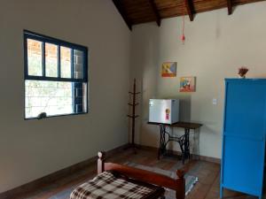 ein Wohnzimmer mit einem Kühlschrank und einem Fenster in der Unterkunft Pousada Recanto dos Pássaros in Cunha