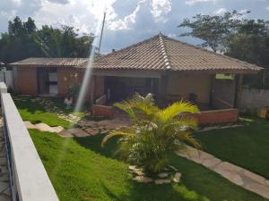 a house with a palm tree in the yard at Chácara Recanto dos Pássaros in São Thomé das Letras