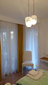 a chair and a chandelier in a room with curtains at NN Luxury Room near Athens Airport in Spata