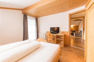 a bedroom with a bed and a desk and a television at Landhaus Pfurtscheller in Neustift im Stubaital