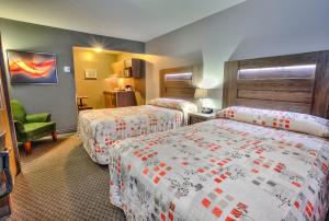 une chambre d'hôtel avec deux lits et une chaise dans l'établissement Hotel et Motel Le Chateauguay, à Québec