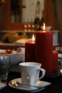 twee rode kaarsen zittend op een tafel met een kopje bij B&B @ Room's in Ieper