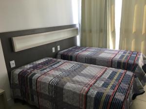 1 dormitorio con 2 camas y manta a cuadros en Apartamento 601 3 Dormitórios, en Torres