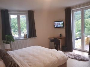 a bedroom with a bed and a desk and windows at Au sommet de la cascade in Stavelot